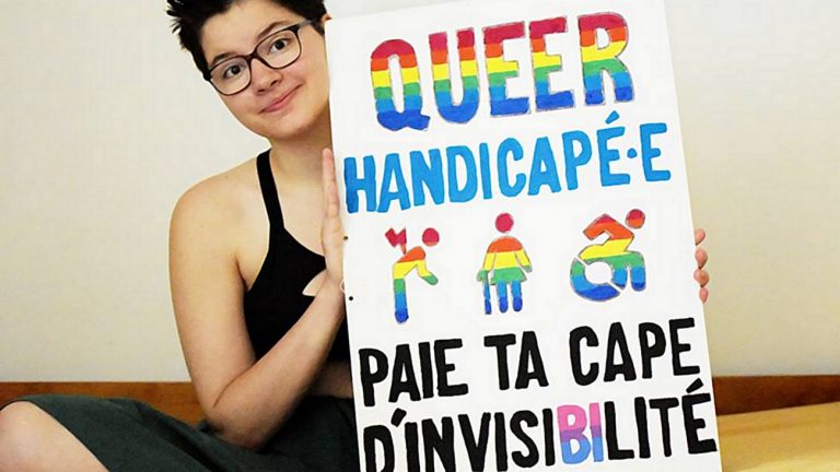 Margot, de « Vivre Avec », tient sa pancarte « Queer handicapé.e paie ta cape d'invisiBIlité », en 2017.
